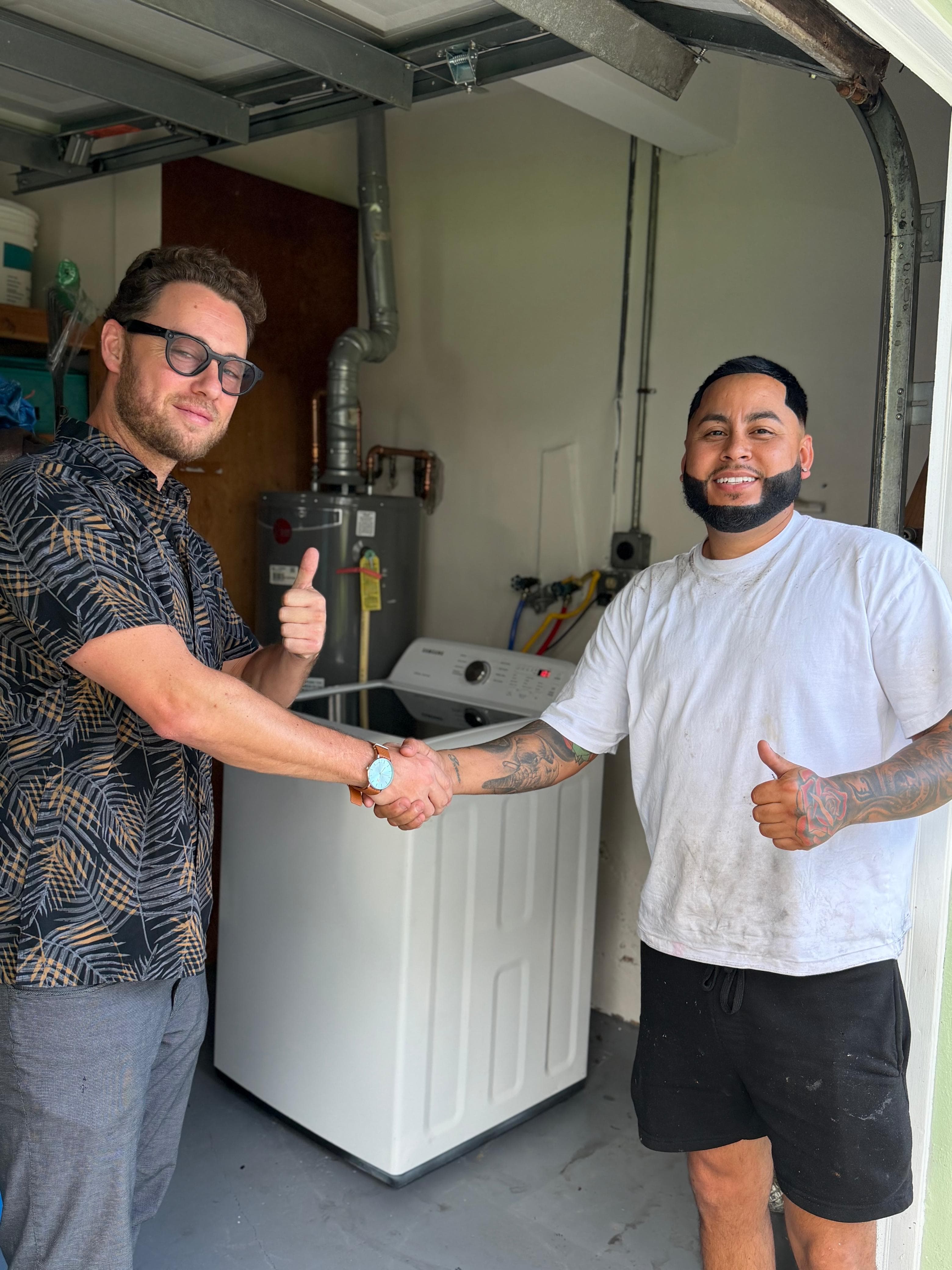 Jonah Stevens shaking hands with a contractor beside a newly installed washer and dryer
